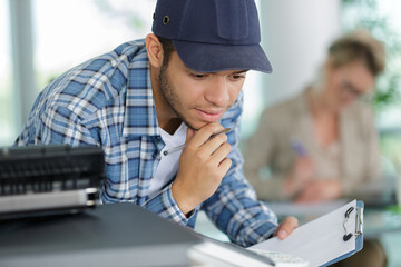 young man servicing a photocopier in an office