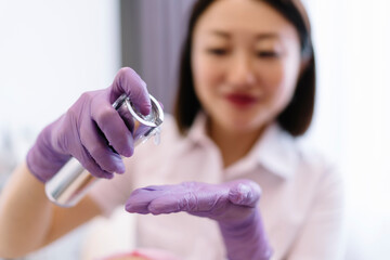 Crop Asian female cosmetologist applying cosmetic product on hand