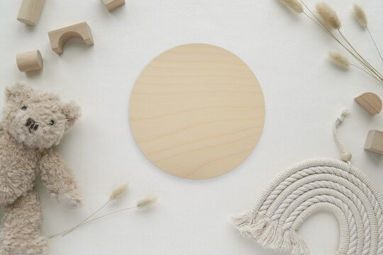 Wood texture baby name sign, round wooden milestone disc mockup, baby toys, bohemian style macrame rainbow, flat lay.