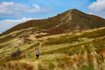 Obraz premium Beautiful fit happy girl in pink jacket enjoys hike in stunning colorful mountain scenery. Spring in the Bieszczady Mountains, Poland, Europe