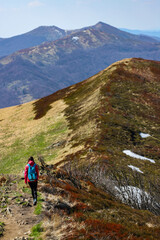 Fototapeta na wymiar Beautiful fit happy girl in pink jacket enjoys hike in stunning colorful mountain scenery. Spring in the Bieszczady Mountains, Poland, Europe