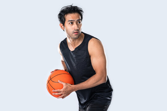 Male basketball player wearing sportswear holding basketball on white background.