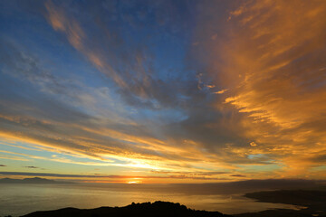 Fototapeta na wymiar Beautiful sunset in Invercargill, New Zealand - orange clouds, blue sky, the Pacific Ocean and mountains 