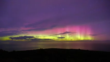 Foto op Canvas Aurora Australis or southern lights in Invercargill, New Zealand  beautiful purple, pink and green lights, with colourful clouds, ocean, night sky and mountains in the background © Lei Zhu NZ