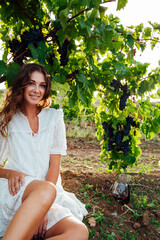 a woman in a white dress sits in a vineyard