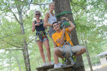 Naklejka na ściany i meble three adults on ledge of tree during adventure course