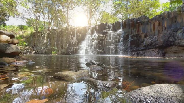 Falling water streams flow on black volcanic stone cascades in waterfall lake.  Rochester Falls waterfall - popular tourist spot in Savanne district in Mauritius.