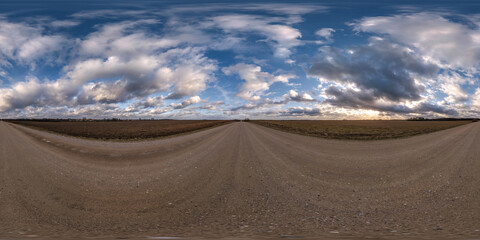 evening 360 hdri panorama on gravel road with clouds on blue sky with halo in equirectangular...