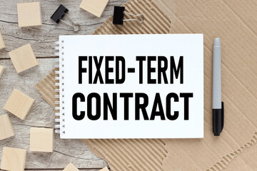 Fixed-Term Contract. open notepad with text. on a wooden table.