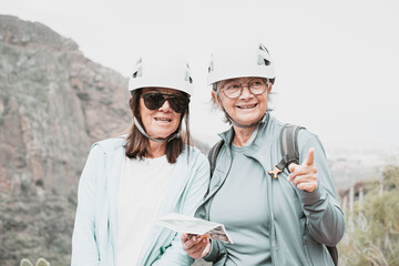 Senior women hikers with helmets standing on the top of mountain - Smiling climbing tourists enjoying holidays and healthy lifestyle - Freedom, success sport concept