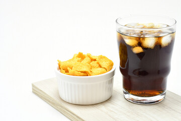 Tiras de maíz y bebida de cola sobre fondo blanco, espacio para texto al lado Izquierdo.