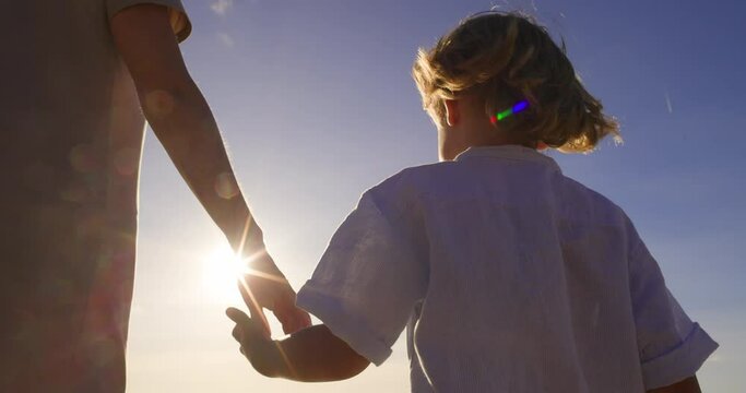 An adopted daughter walks hand in hand with her new mother, basking in the summer sunset. Gradually emerging trust and love for new adoptive mother. A walk in nature, woman and girl walking by hand
