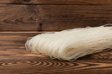Funchoza.Dried raw rice noodles and rice on a brown wooden background.Noodles with rice flour. Diet food. Healthy food. Place for text. Place for copying.