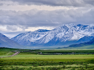 Beautiful rugged and snow-covered Mountain peaks of the Brooks Range in Alaska between the Coldfoot Camp and Prudhoe Bay with the Alaska Oil Pipeline traversing the treeless Tundra