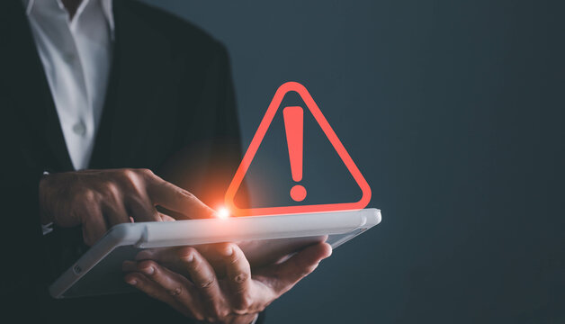 Businessman using tablet with triangle caution warning sing for notification error and maintenance concept.