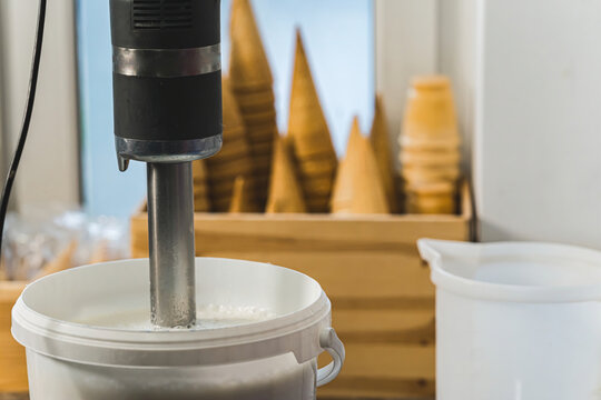 Mixing milk in a white container with professional blender for ice cream. High quality photo