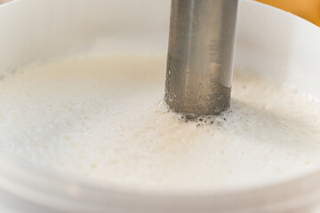 Ice cream preparation. Mixing milk with a blender close view. High quality photo