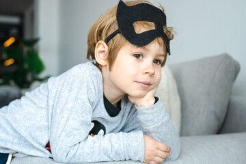 Little Boy with carnival costume . Costume of bat lying on sofa.