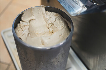 Close shot of vanilla ice cream in a steel container from batch freezer machine. High quality photo