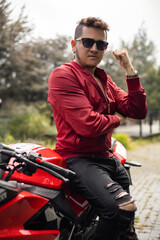 Fototapeta na wymiar sport motorcycle details with young man who has short hair and wears sunglasses, casual jacket, adventurous lifestyle, male model