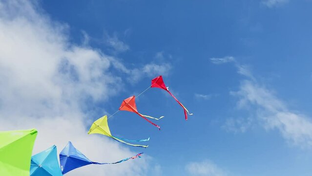 Many beautiful colorful kites fly over blue sky and clouds