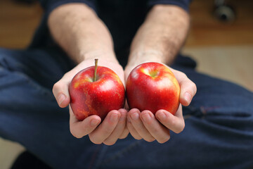 a person holding two red apples