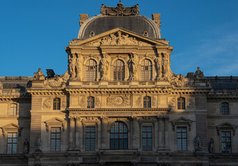 Fototapeta na wymiar Paris, France - 02 21 2023: Details of facade of the Louvre museum and Louvre pyramid from the Napoleon courtyard