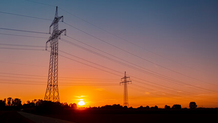 Beautiful sunset with a dramatic sky and overland high voltage lines near Tabertshausen, Bavaria,...