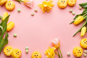Frame composition made of macaroon chicks, yellow tulips and daffodils, candy chocolate eggs over...