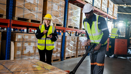 Warehouse workers team pulling a pallet truck and checking stock of goods before distribute to customer.