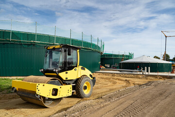 Walze walzt das Erdreich platt, vor einem neu errichteten Gärbehälter einer Biogasanlage.