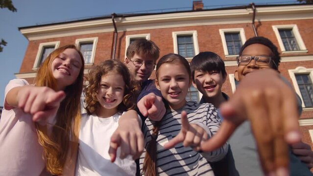 Middle school students point at camera and laugh outdoors. Realtime
