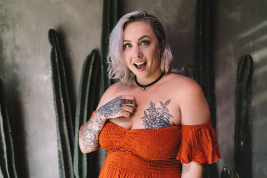 Happy woman in trendy dress with tattoo standing in cafe