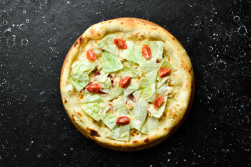 Caesar pizza with chicken. classic pizza On a black stone background. Top view.