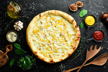 Classic pizza with chicken, pineapple and cheese. Cheese pizza. On a black stone background. Top view.