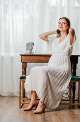 a pregnant girl in a white dress sits at the table