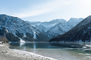 the beautiful lake plansee photographed in the day with the mountains covered with snow and the lake plansee in the foreground with crystal clear water