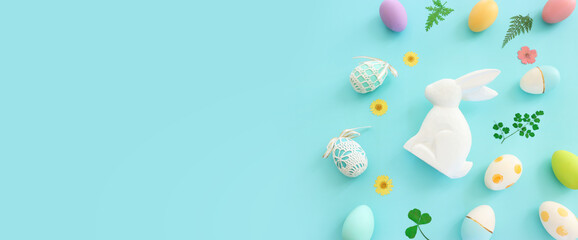 Cute bunny next to easter colorful eggs over blue pastel background