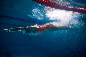 Developing speed. Professional female swimmer training in swimming pool indoor. Underwater view....
