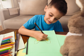 Happy brazilian boy with pencil drawing easter bunny in living room