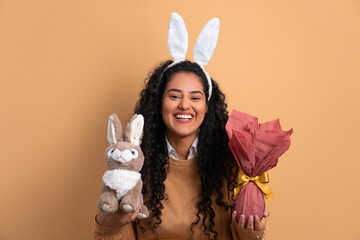 happy african american woman celebrating easter egg gift in beige studio background. holiday,...