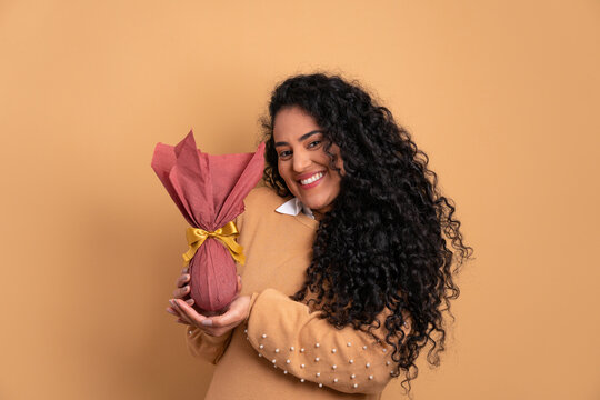 cheerful afro brazilian woman with easter egg in beige colors. holiday, easter, celebration concept.