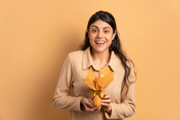 surprised caucasian woman celebrating easter egg gift in beige colors. holiday, easter, celebration concept.