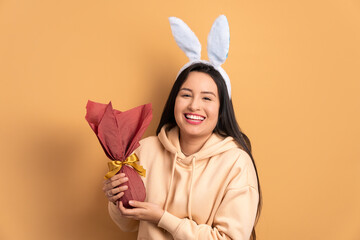 happy young woman celebrating easter egg gift in beige background. holiday, easter, celebration...