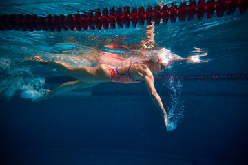 Coordinated movements, speed. Professional female swimmer training in swimming pool indoor....