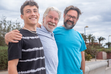 Portrait of three males laughing, grandfather, son and grandson stay together in outdoors, smiling...