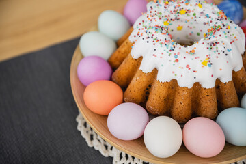 High angle view of sweet Easter cake and painted pastel colors eggs on table at home.