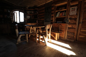 The kitchen is completely made of wood in a traditional style in a Ukrainian house, floor, table, chairs, in the light of the morning sun, but books on the shelves