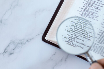 Magnifying glass over open holy buble book of psalms 139 verses. Top table view. Copy space....