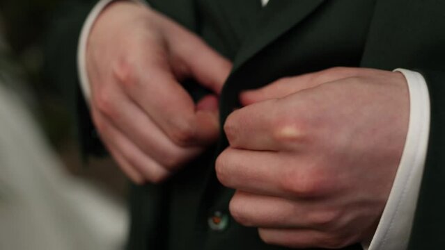 a man in a suit fastens a button at a wedding business man